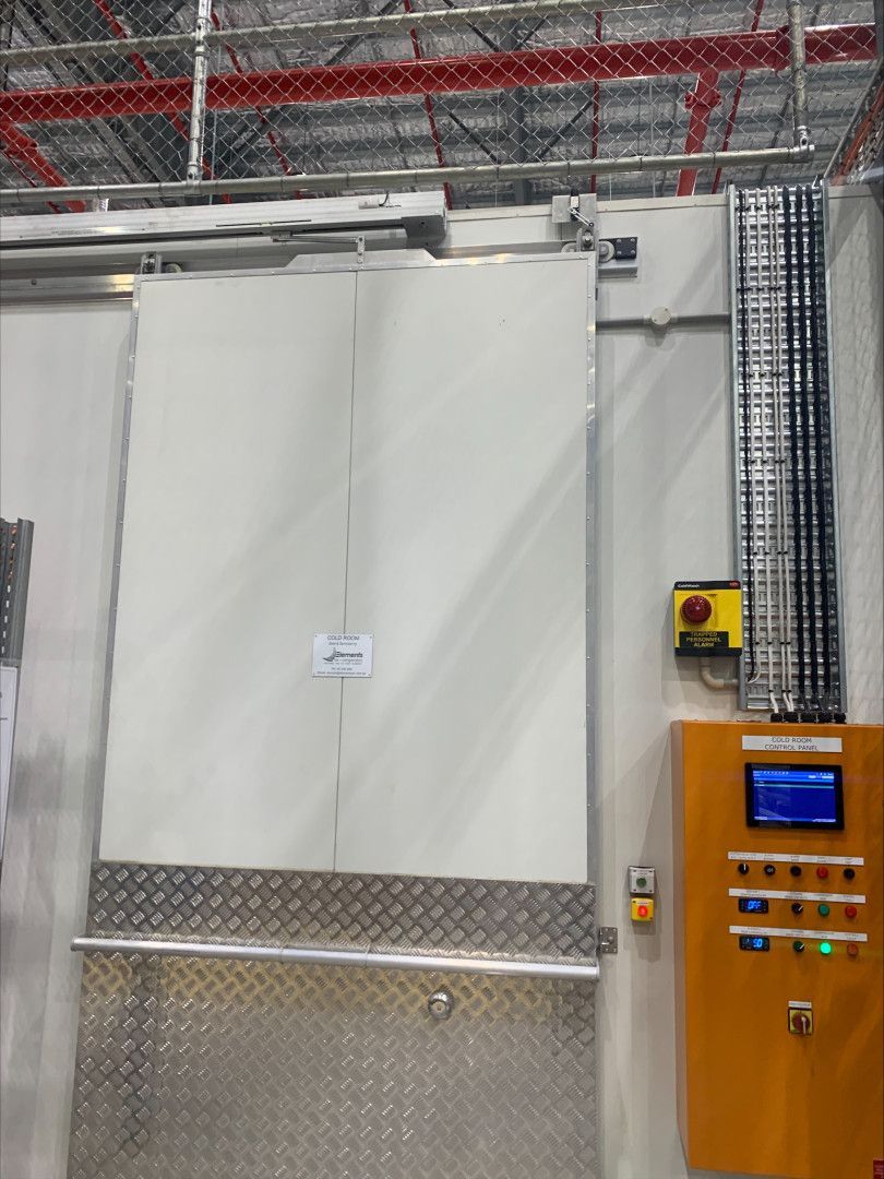 Large, white industrial door with diamond-plate base, and control panel.— Elements Air & Refrigeration In Westcourt, QLD