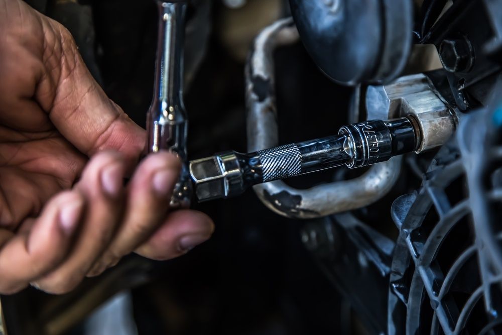 A Man is Fixing a Refrigerator With a Screwdriver — Elements Air & Refrigeration In Westcourt, QLD