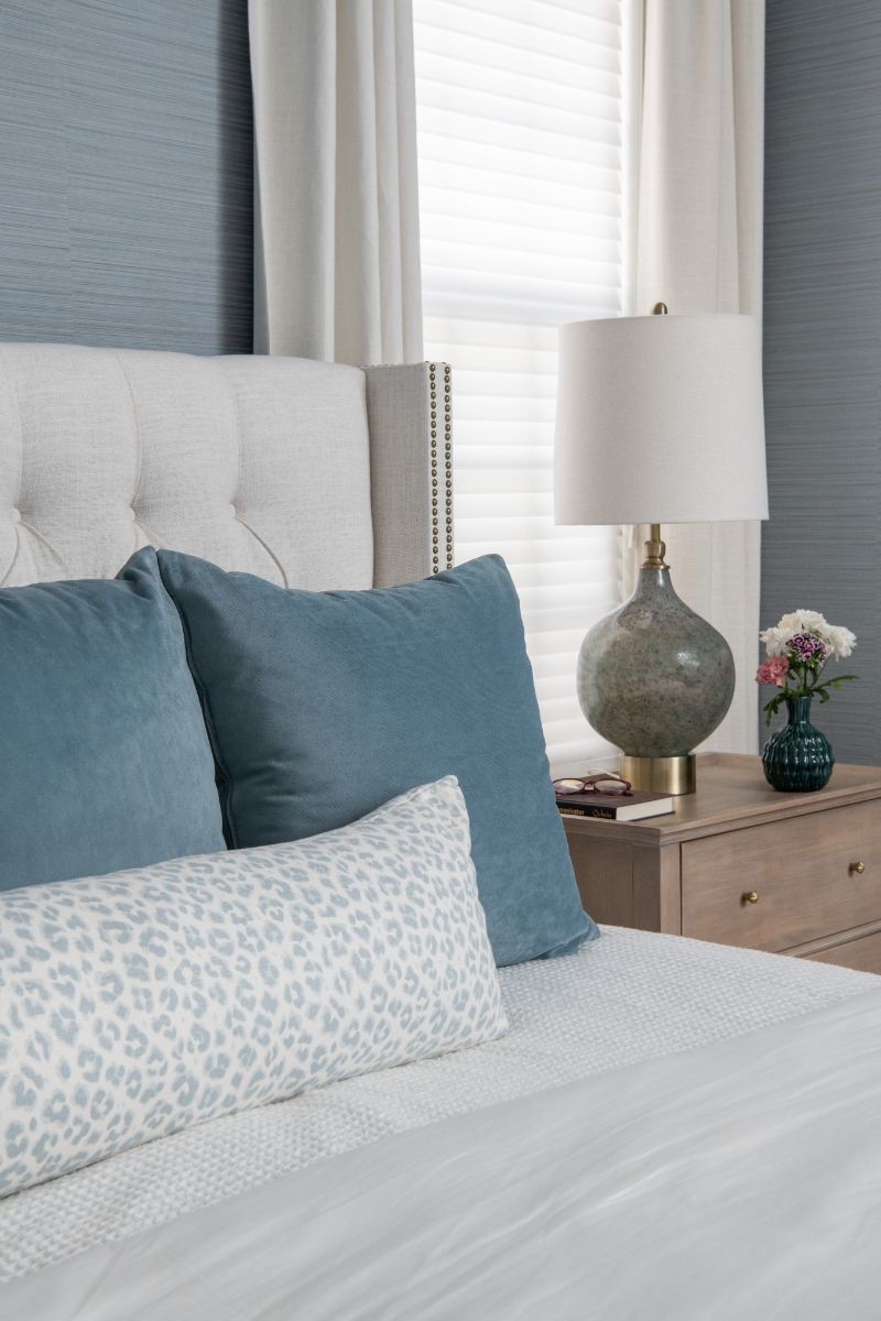 A bedroom with a bed , nightstand , lamp and blue and white pillows - Charlotte, NC