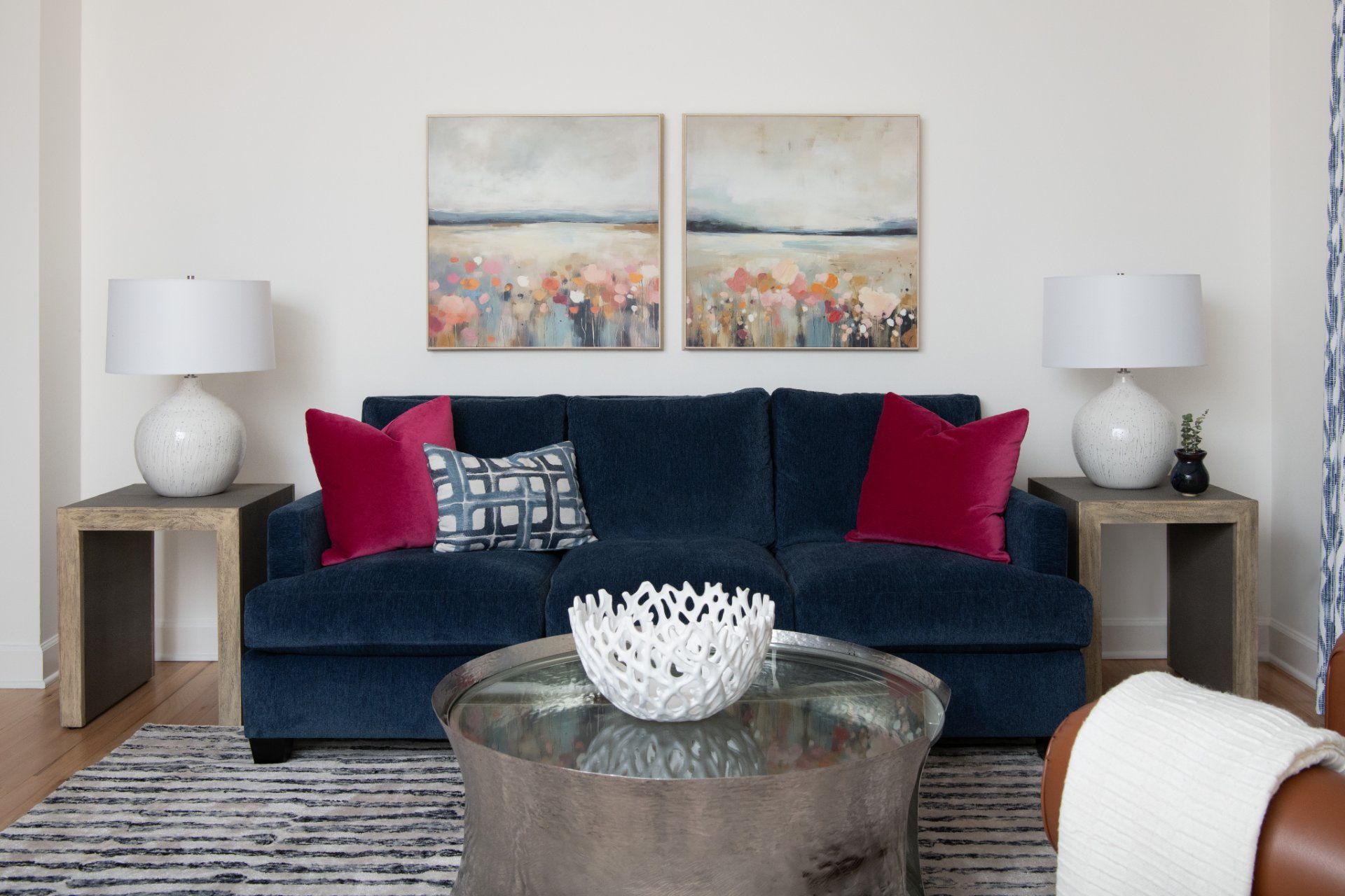 Living room with blue sofa, pink pillows, abstract art, and round coffee table | Charlotte, NC | An Inspiring Home
