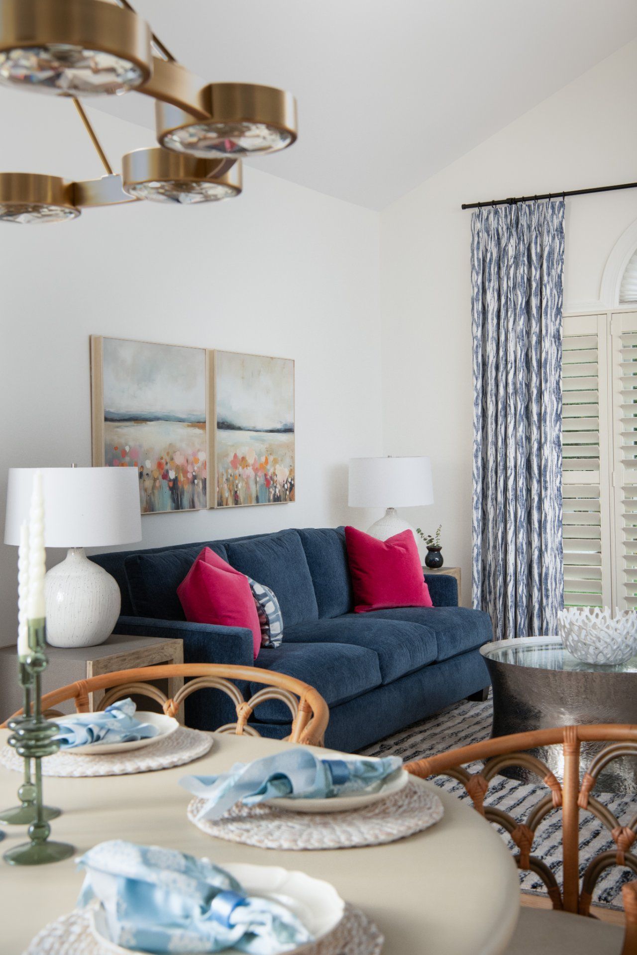 Living room with blue sofa, pink pillows, floral curtains, and a round dining table | Charlotte, NC | An Inspiring Home