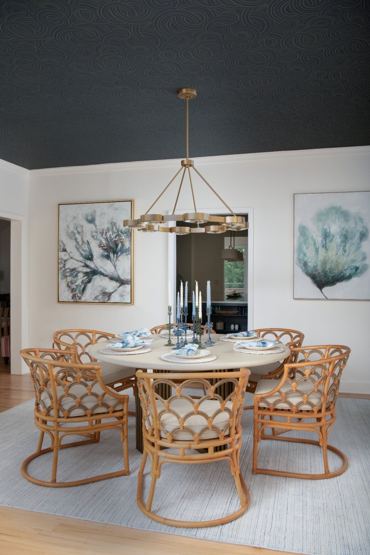 Dining room with round table, rattan chairs, and chandelier. White walls, art, dark ceiling | Charlotte, NC | An Inspiring Home