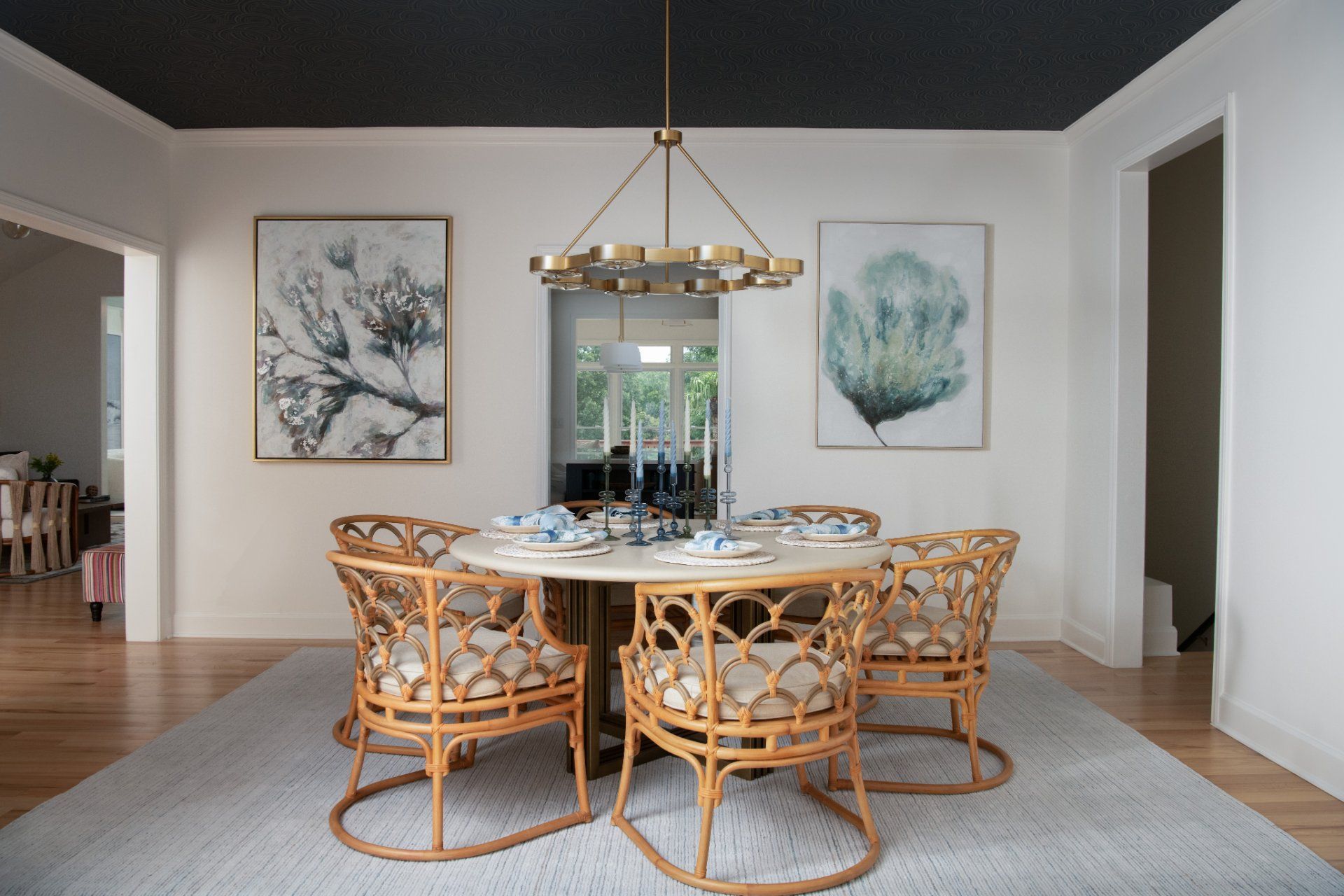 Dining room with a round table, rattan chairs, art, and a gold chandelier | Charlotte, NC | An Inspiring Home