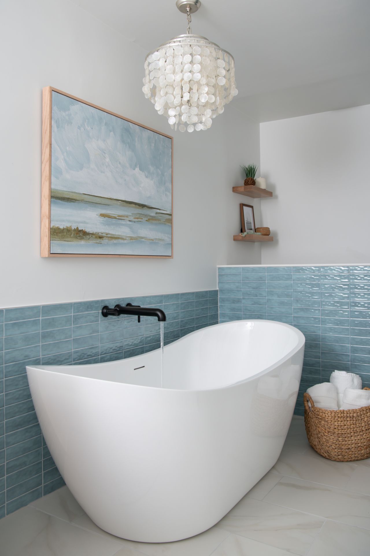 Modern white bathtub in a blue-tiled bathroom with a shell chandelier and artwork | Charlotte, NC | An Inspiring Home