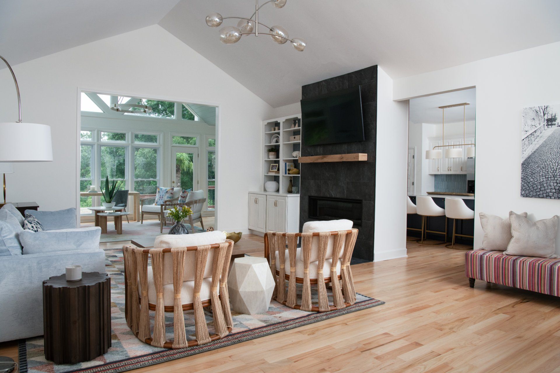 Bright, modern living room with light wood floors, a fireplace, and a view into a sunroom | Charlotte, NC | An Inspiring Home