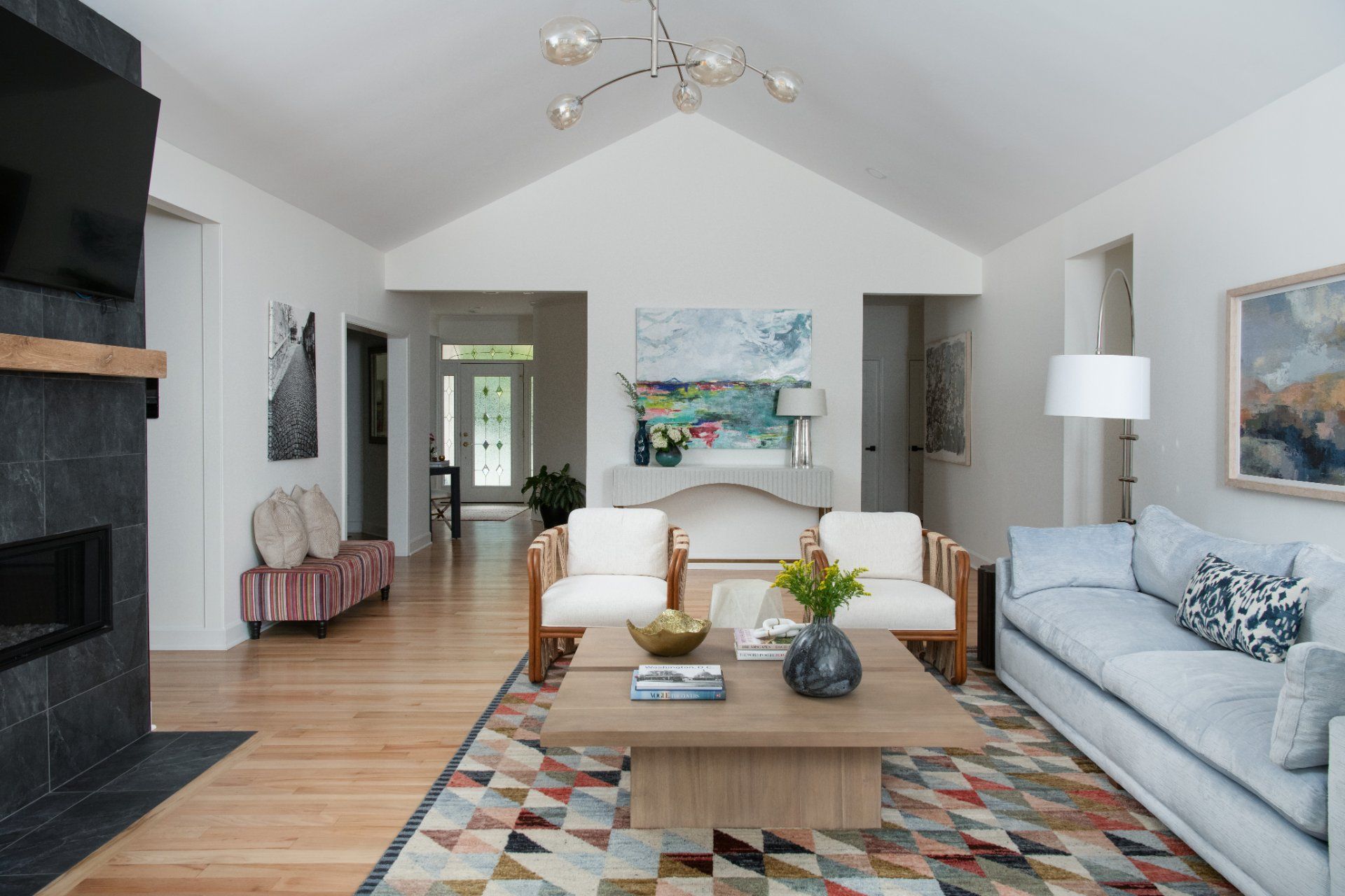 Living room with vaulted ceiling, fireplace, light wood floors, and colorful rug | Charlotte, NC | An Inspiring Home
