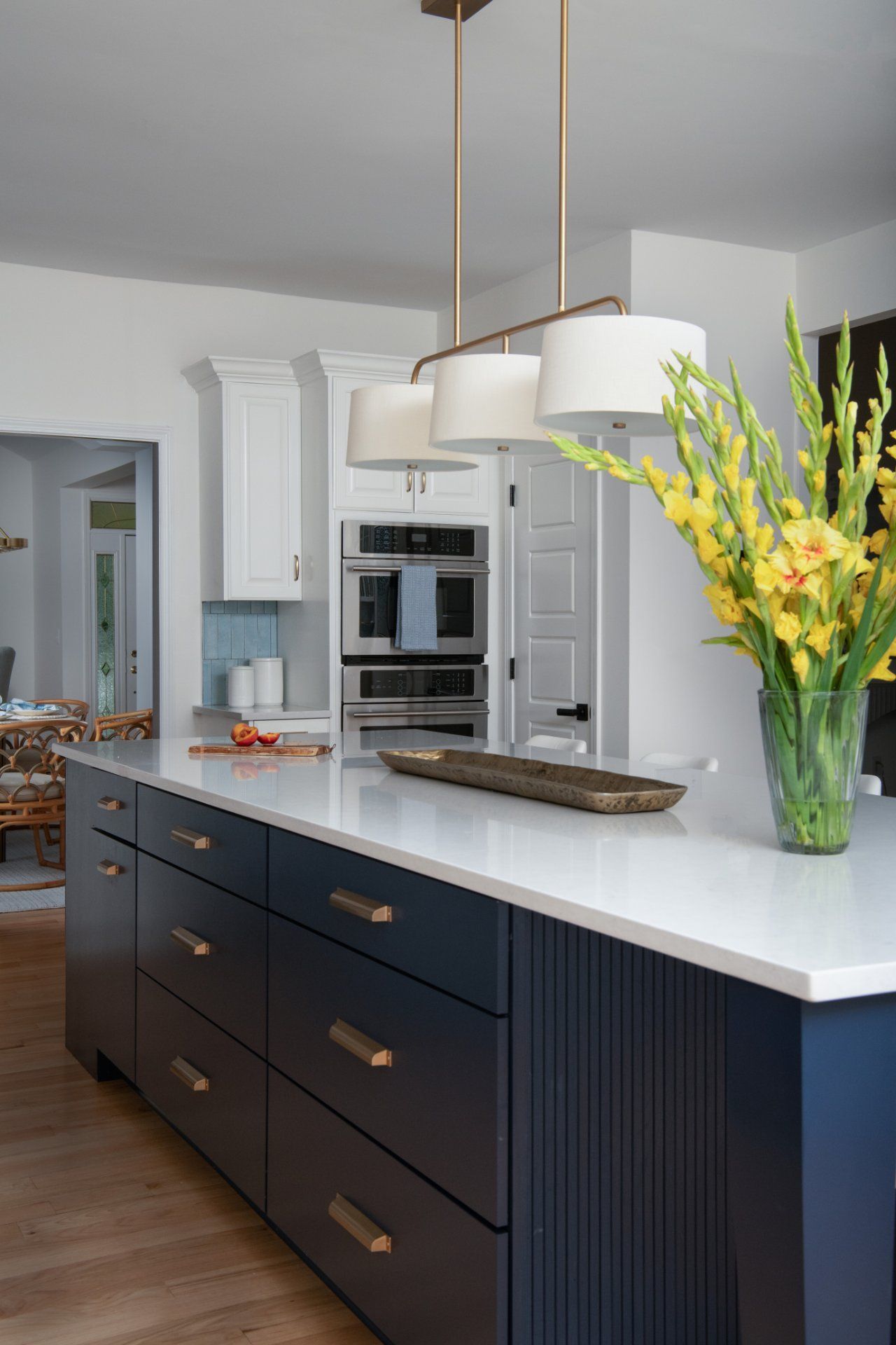 Navy blue kitchen island with white countertop, gold hardware, and pendant lights. Yellow flowers in vase | Charlotte, NC | An Inspiring Home