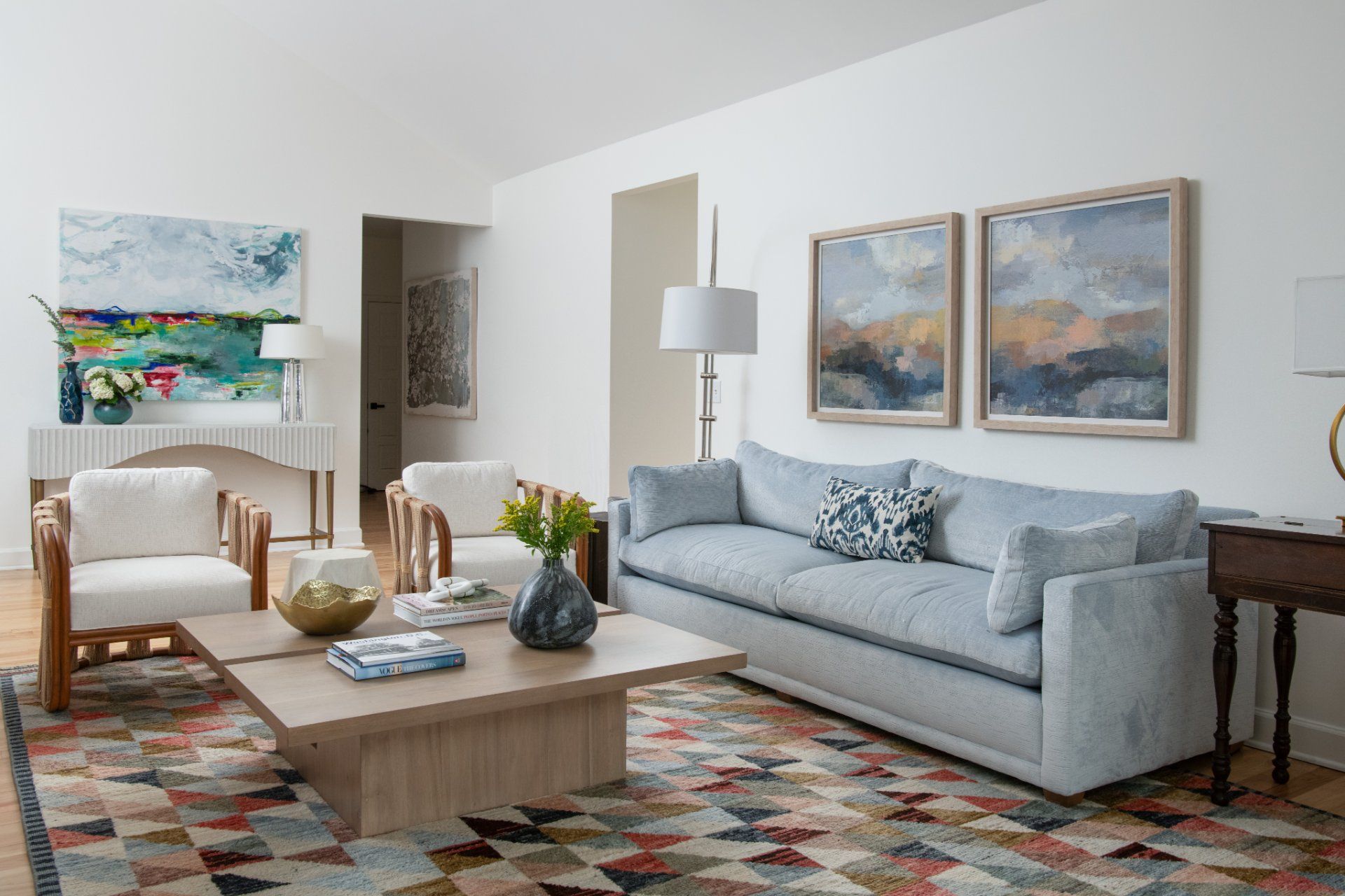 Living room with light blue sofa, colorful rug, white walls, artwork, and wood furniture | Charlotte, NC | An Inspiring Home