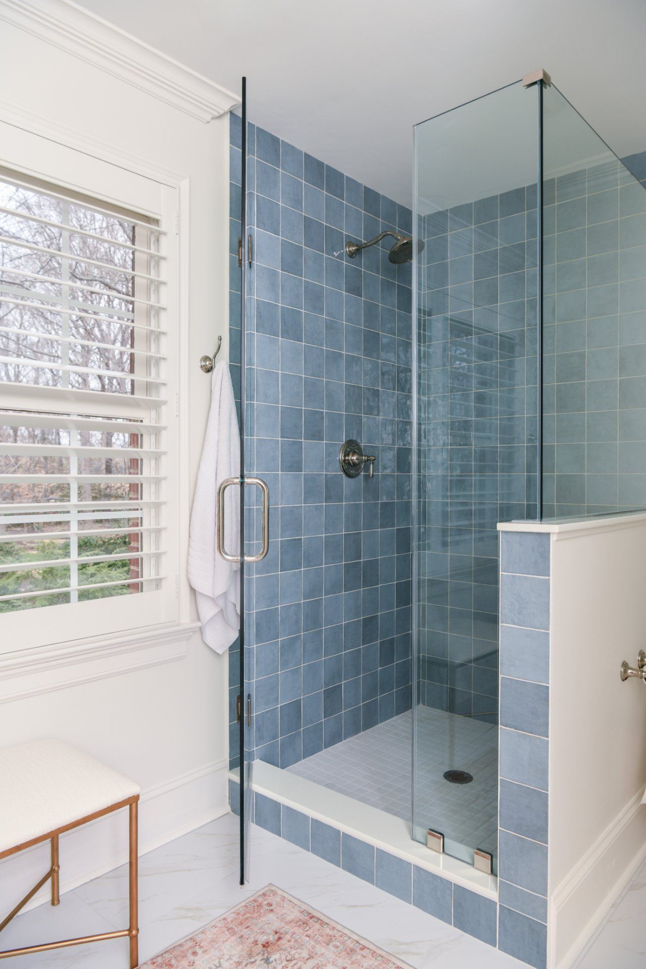 Blue-tiled glass shower with white trim beside a window in a bright bathroom | Weddington, NC | An Inspiring Home