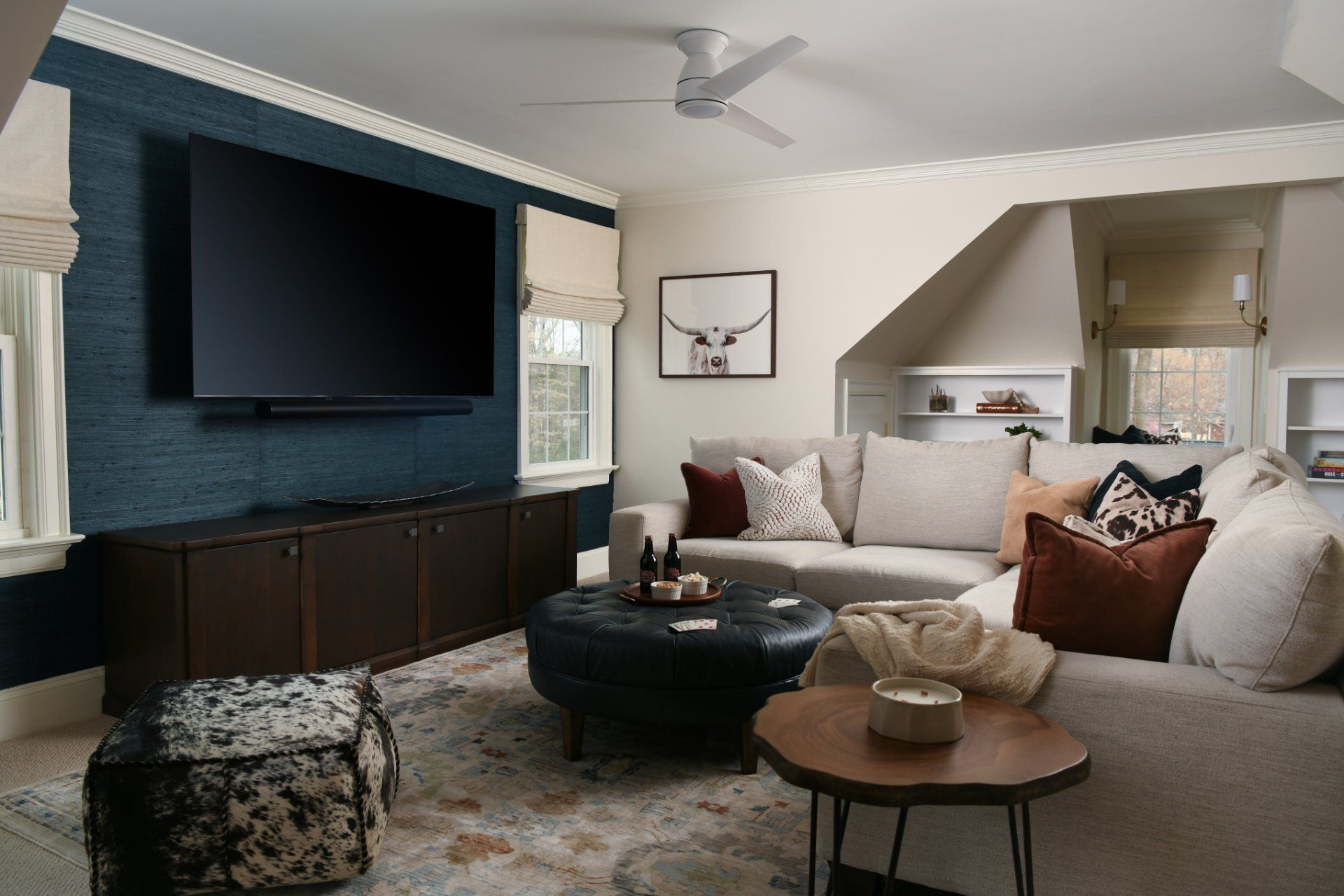 Modern living room with wall-mounted TV, sectional sofa, and round coffee tables in neutral tones | Weddington, NC | An Inspiring Home