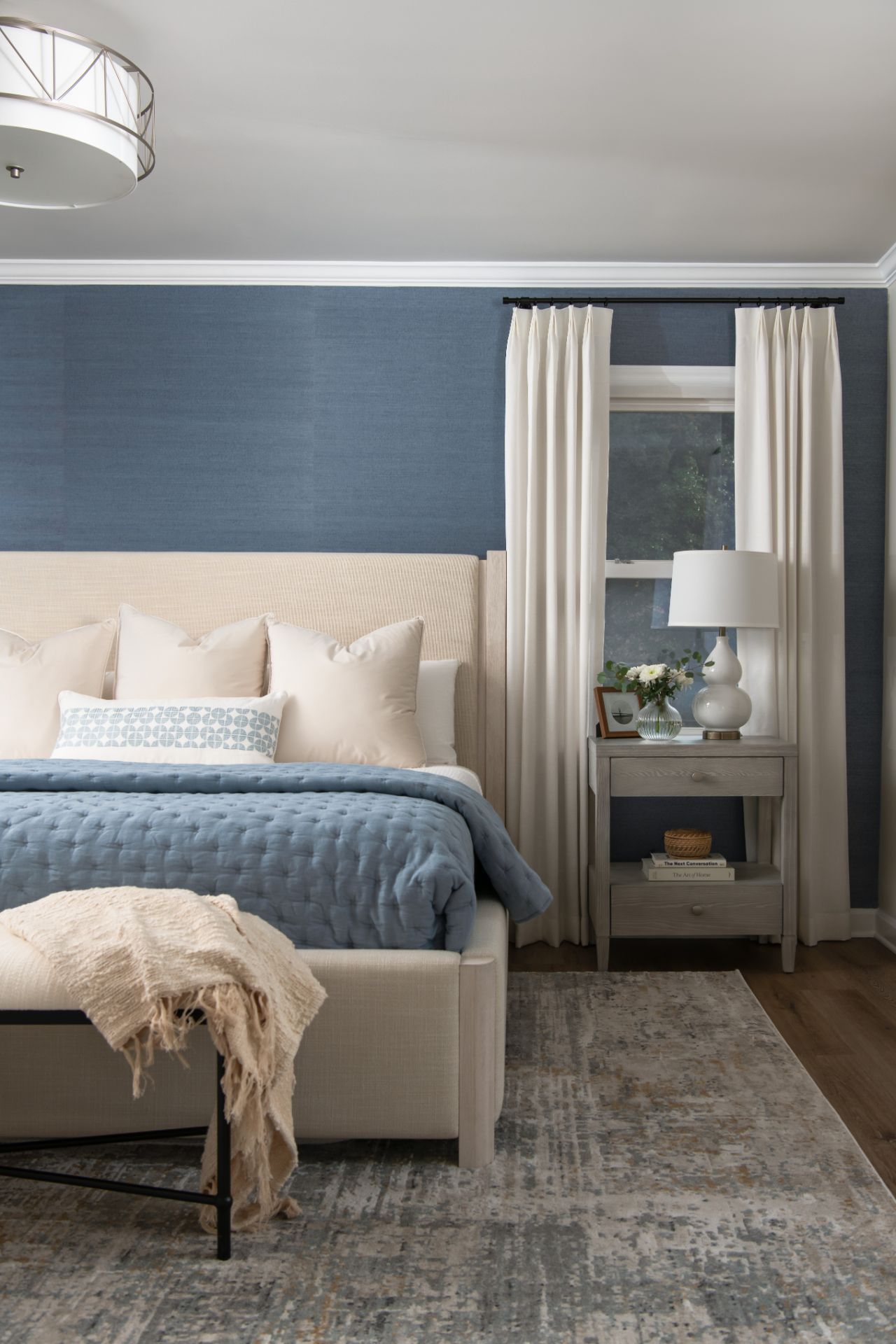 Bedroom with blue textured wall, beige bed, nightstand, cream curtains, and patterned rug | Charlotte, NC | An Inspiring Home