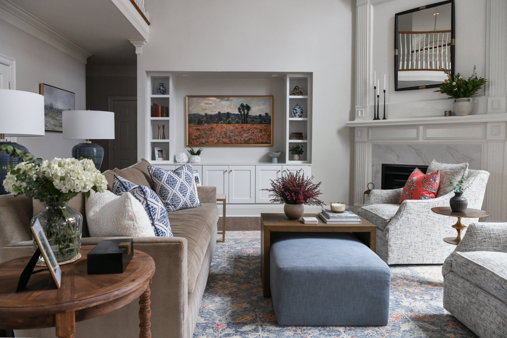 Cozy living room with beige sofas, blue ottoman, fireplace, built-in shelves, and floral decor | Weddington, NC | An Inspiring Home