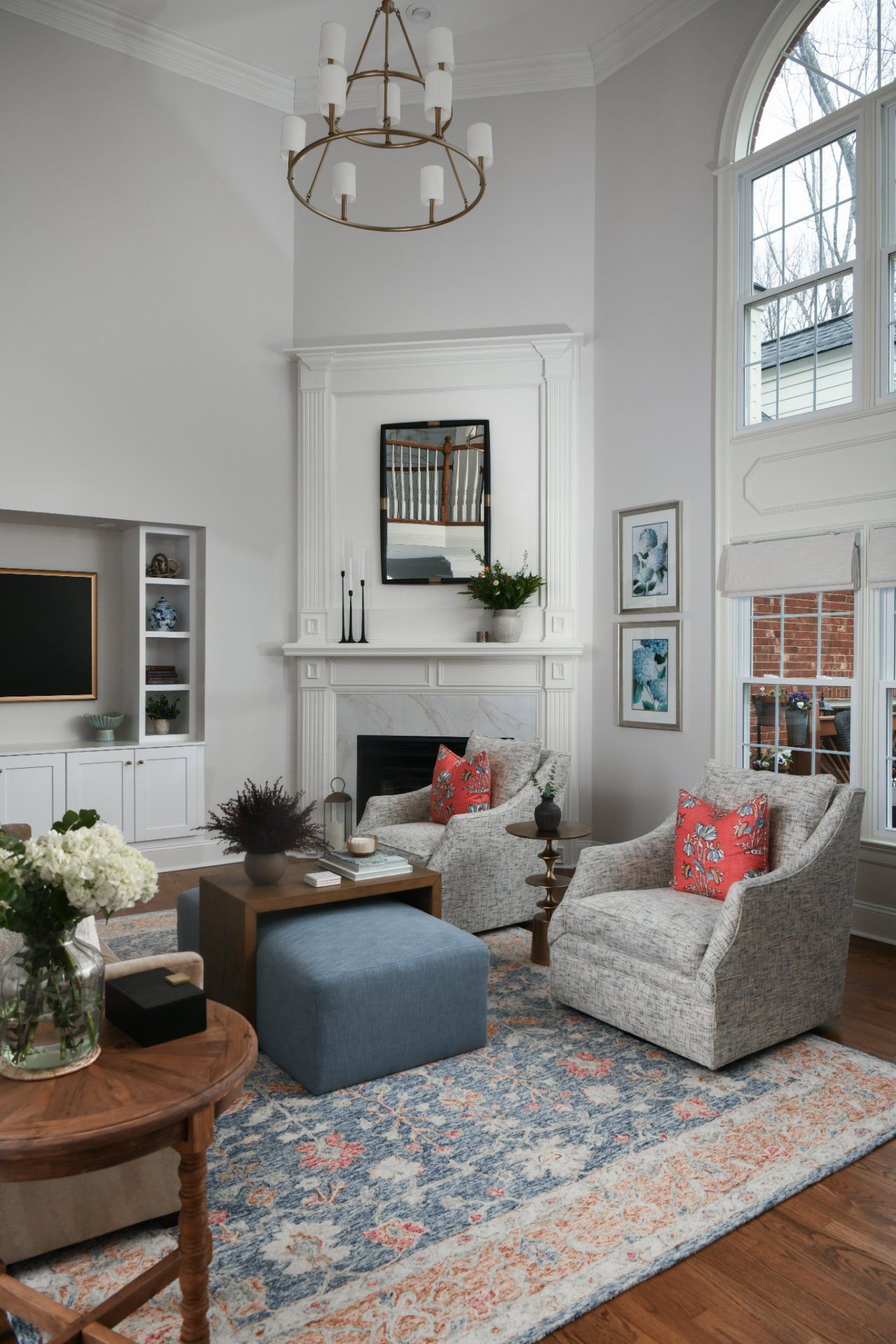 Bright living room with a fireplace, large windows, patterned chairs, blue ottoman, and colorful rug | Weddington, NC | An Inspiring Home
