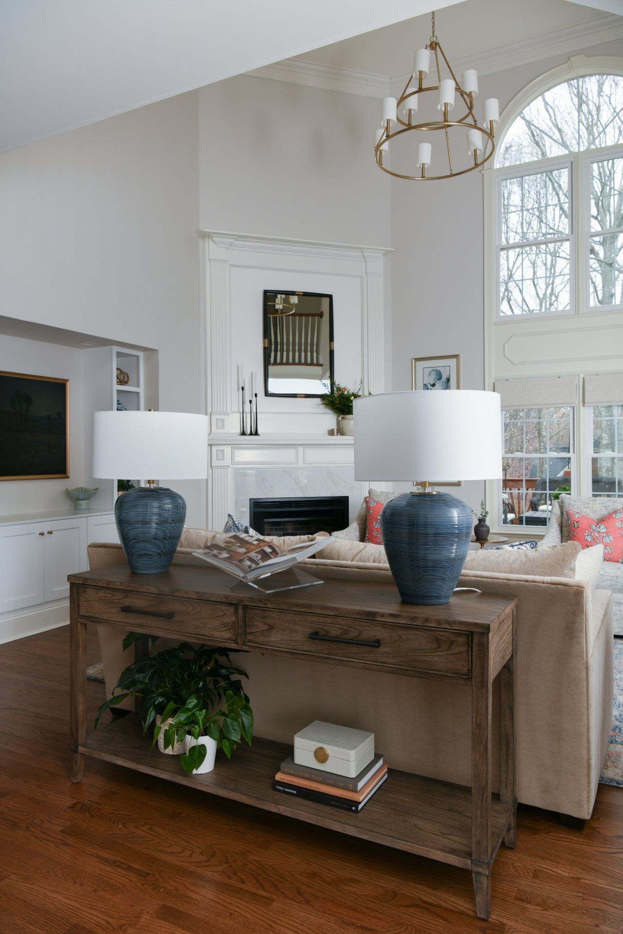 Bright living room with white fireplace, tall windows, and a rustic console with blue lamps and decor | Weddington, NC | An Inspiring Home