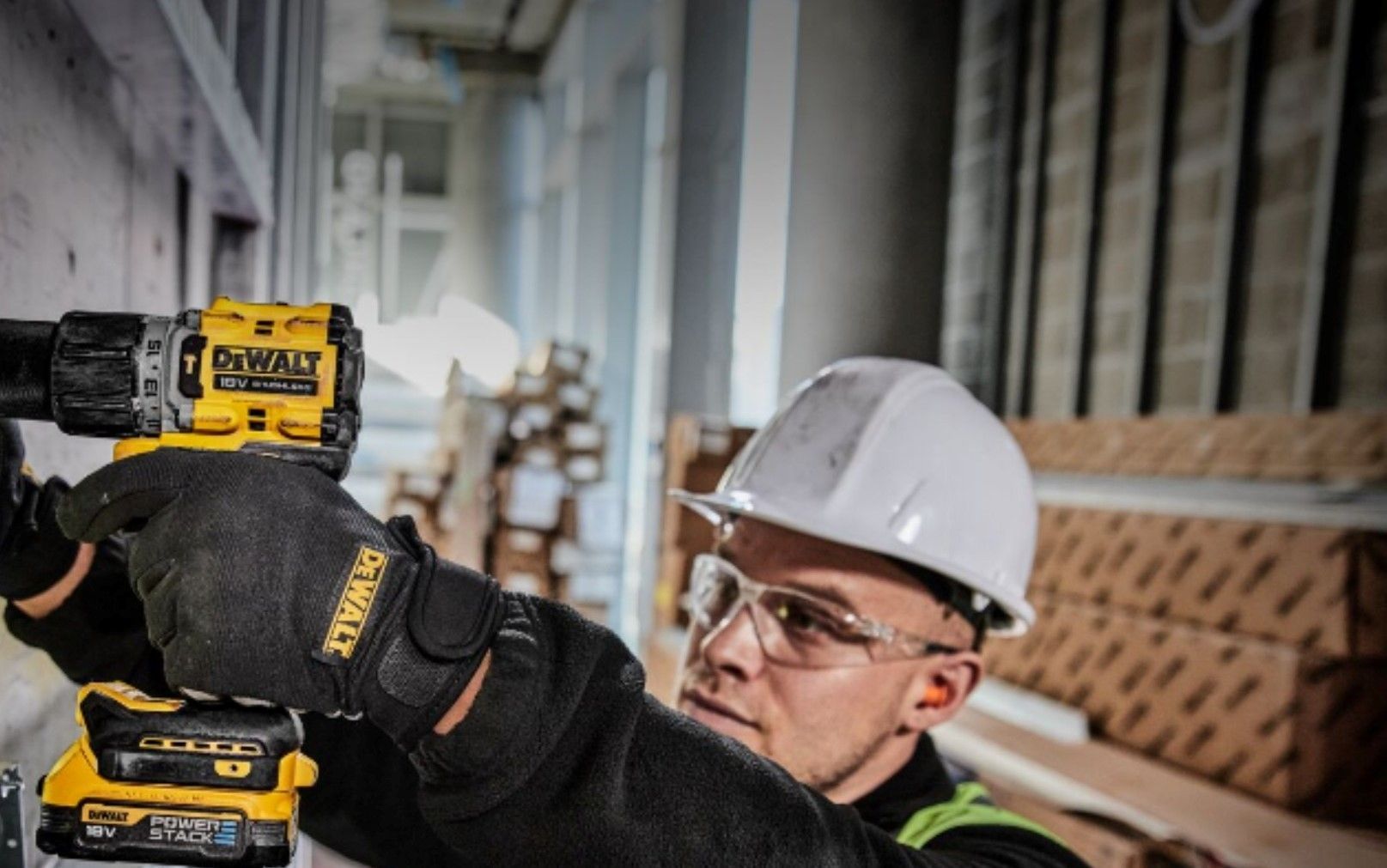 Un hombre que lleva casco y gafas de seguridad está utilizando un taladro en una pared.