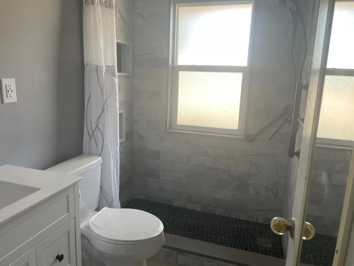 A bathroom with a toilet , sink , shower and window.