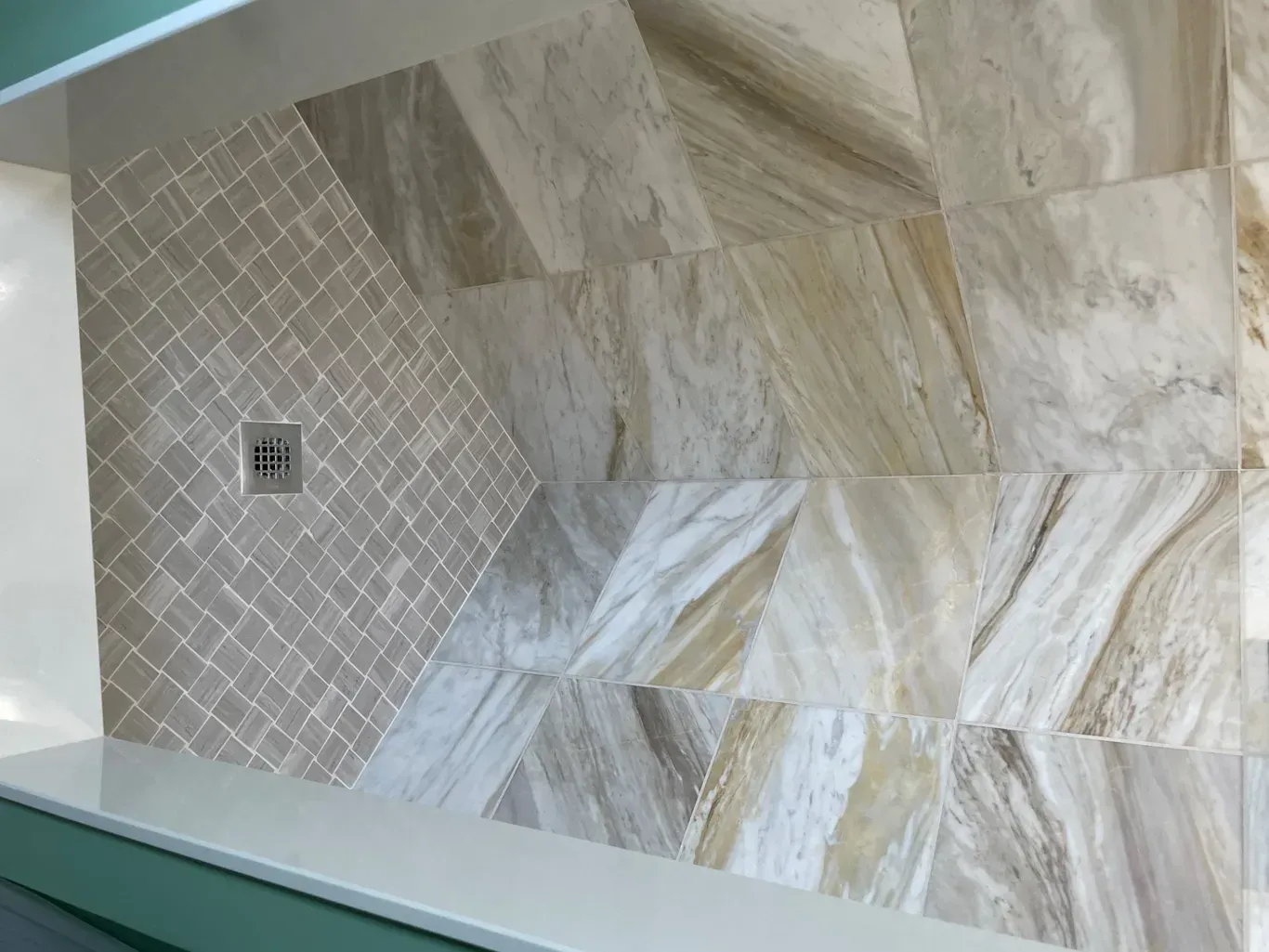 A shower stall with tiles on the wall and a drain.