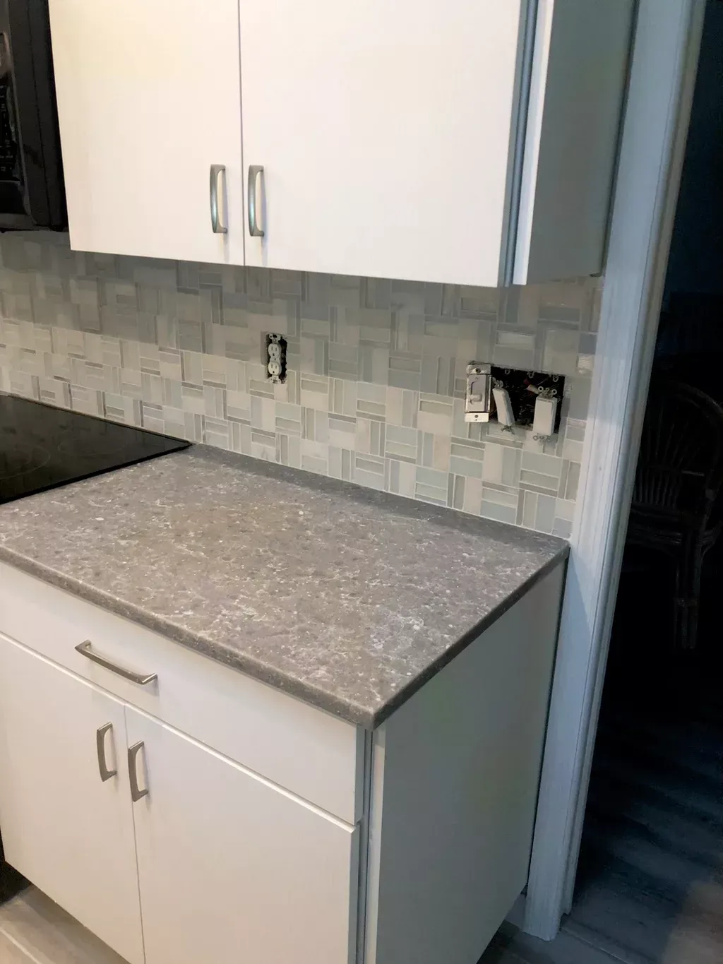 A kitchen with white cabinets and a gray counter top.
