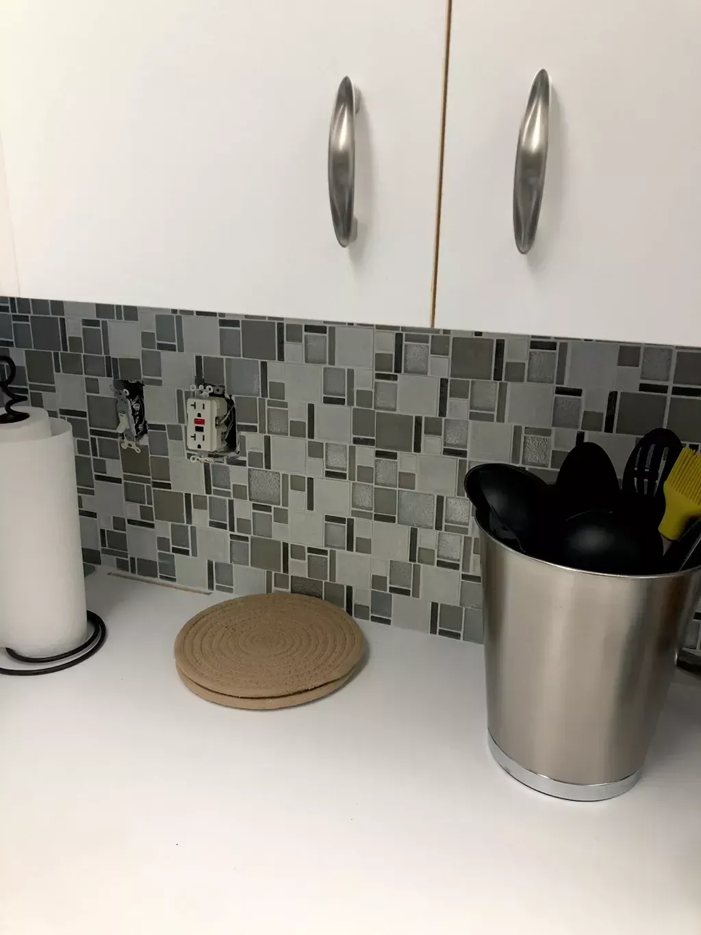 A kitchen counter with a bucket of utensils on it