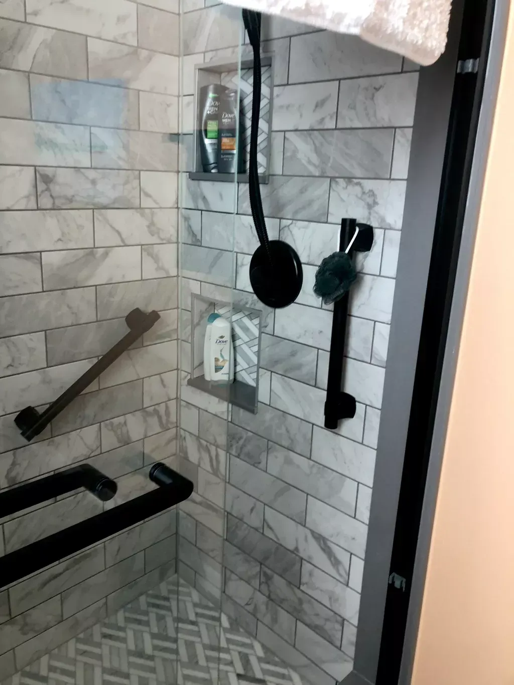 A shower with a sliding glass door and black handles