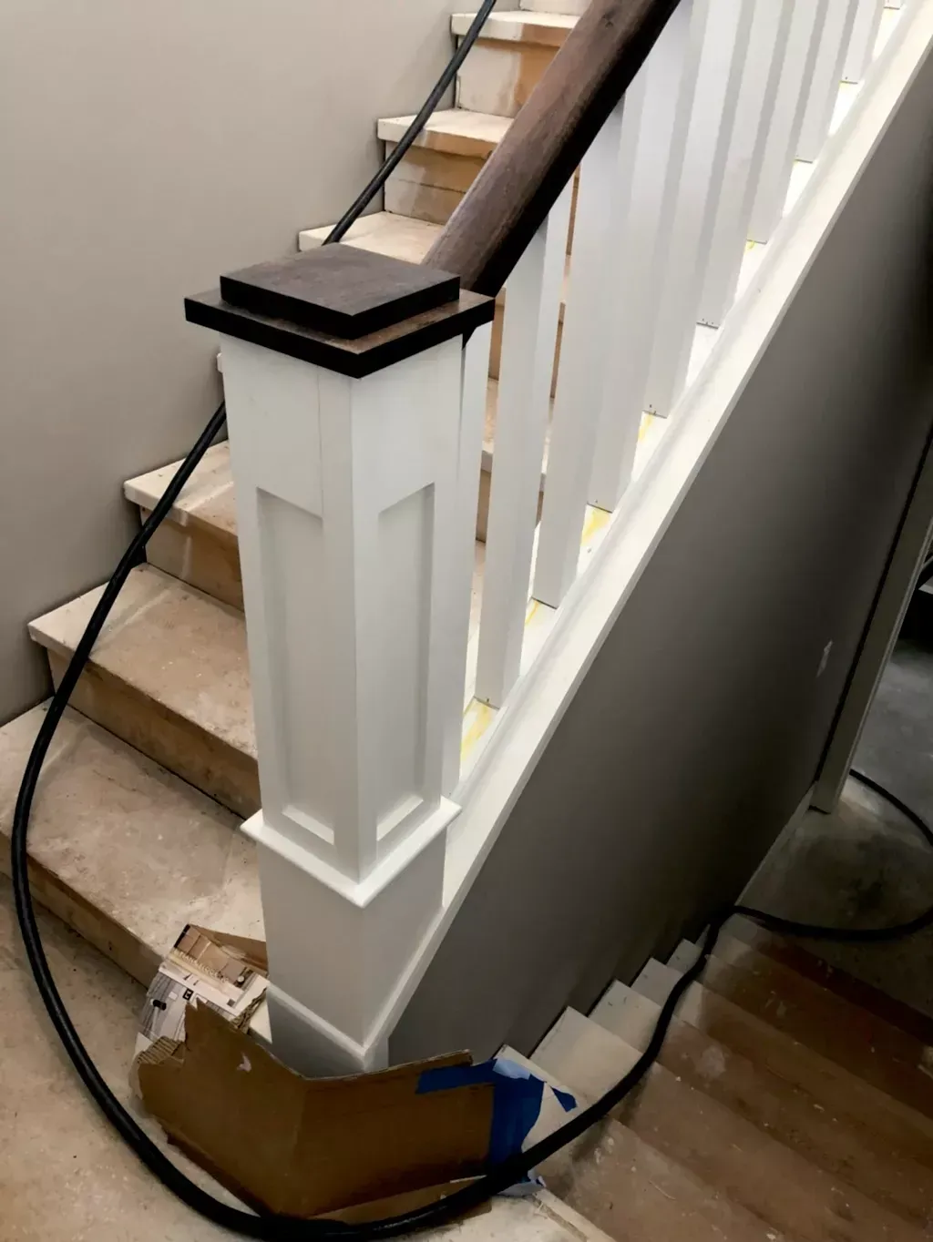 A staircase with a white railing is being painted