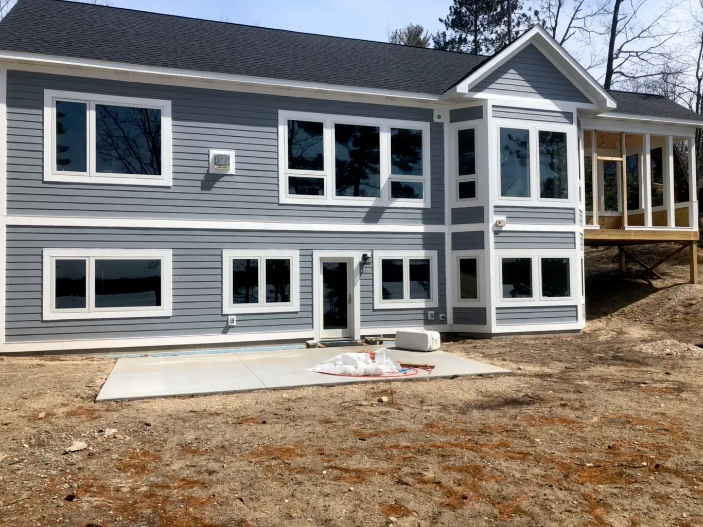 A large house with a lot of windows is sitting on top of a dirt hill.