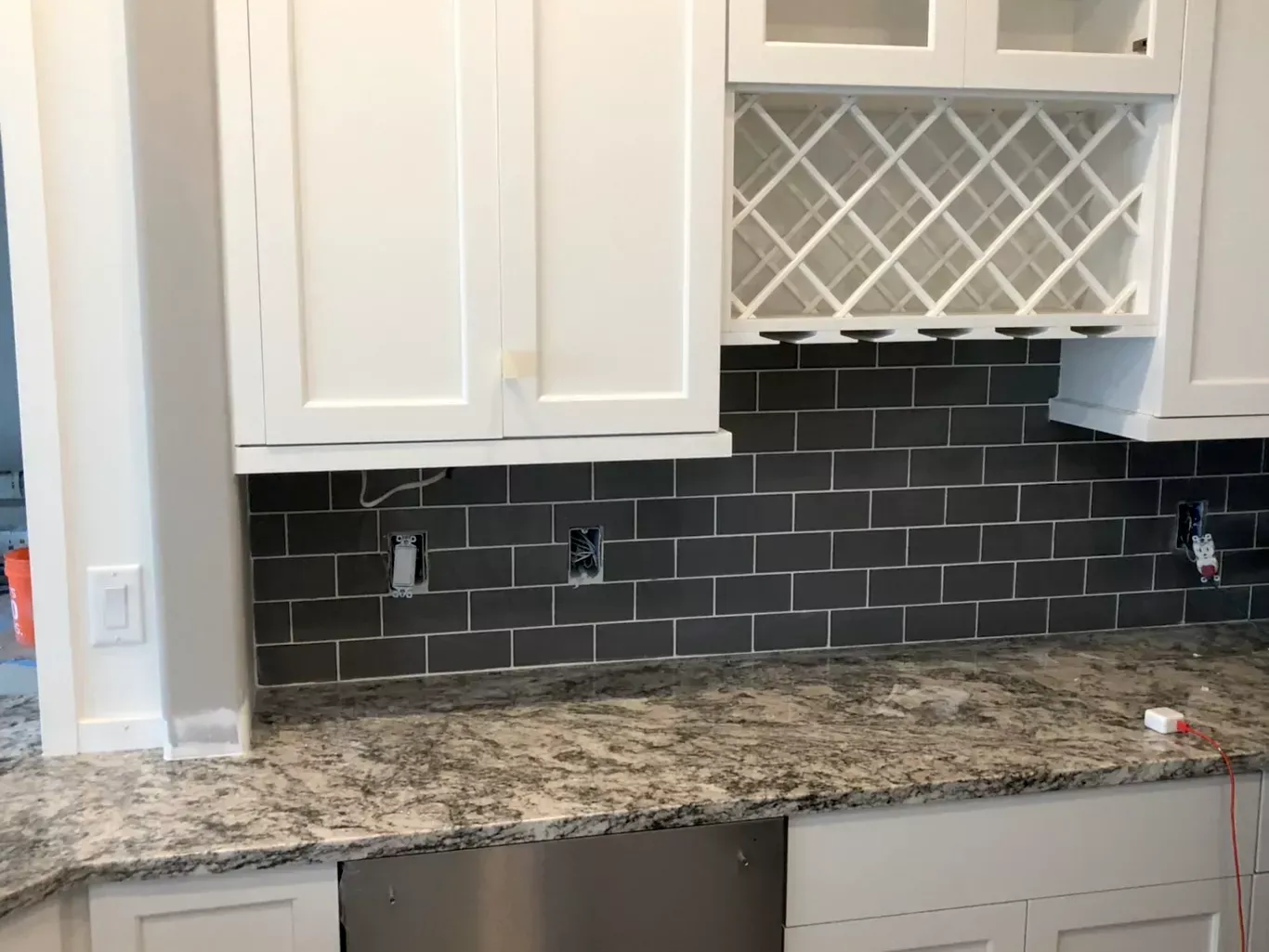 A kitchen with granite counter tops , stainless steel appliances , and a wine rack.