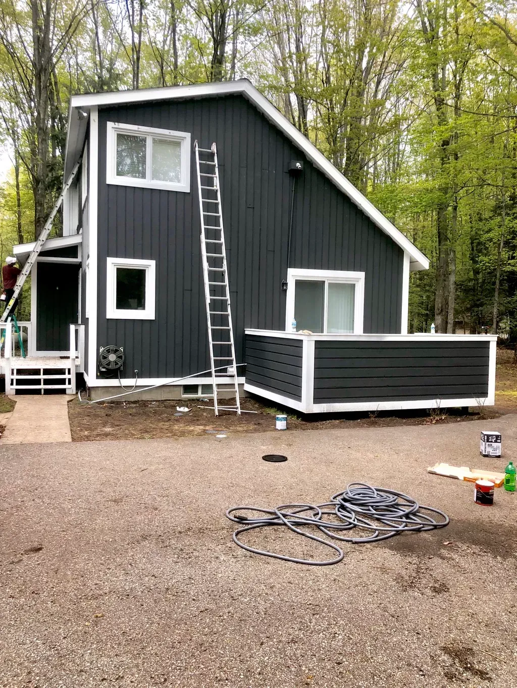 A house with a ladder on the side of it is being painted.