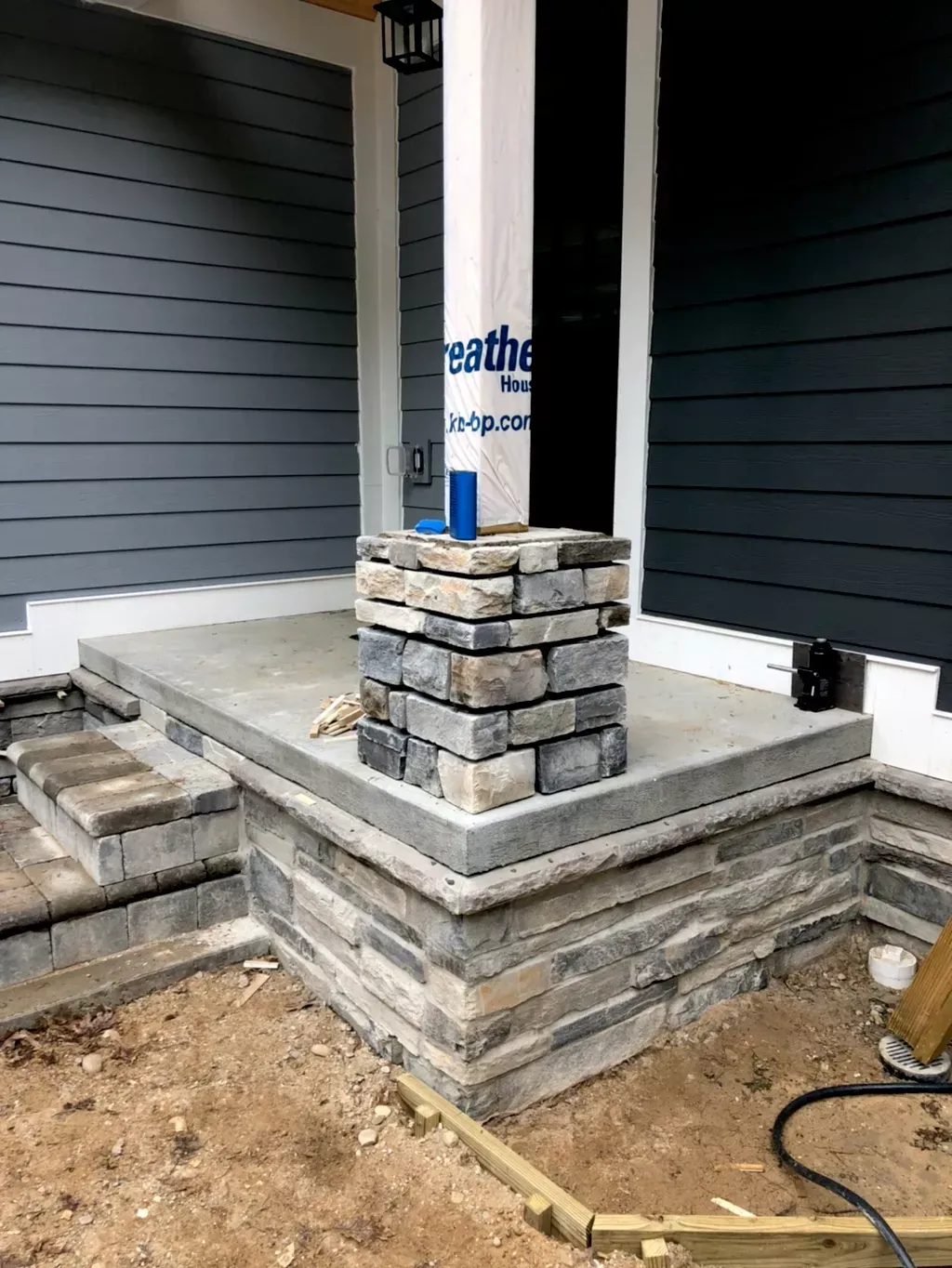 A stone porch is being built on the side of a house.