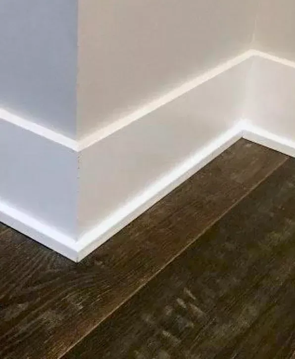 A close up of a white molding on a wooden floor.