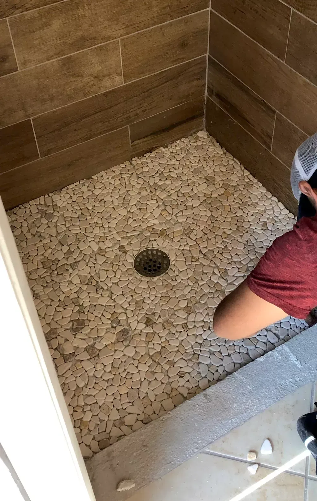 A man is standing in a shower looking at the floor.