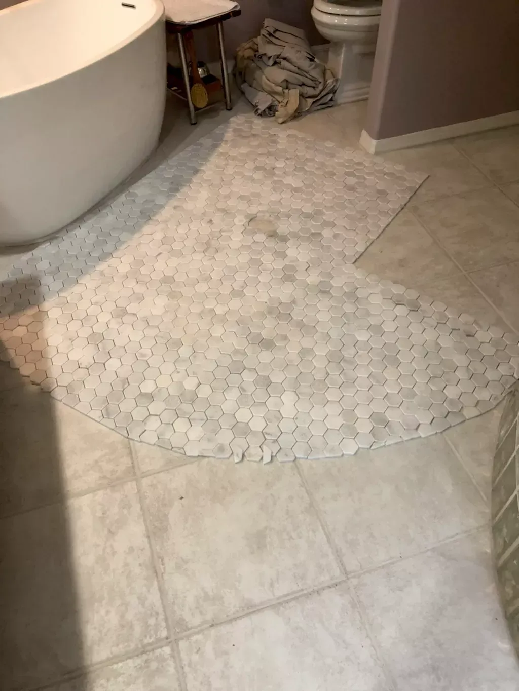 A bathroom with a bathtub , toilet , and tile floor.