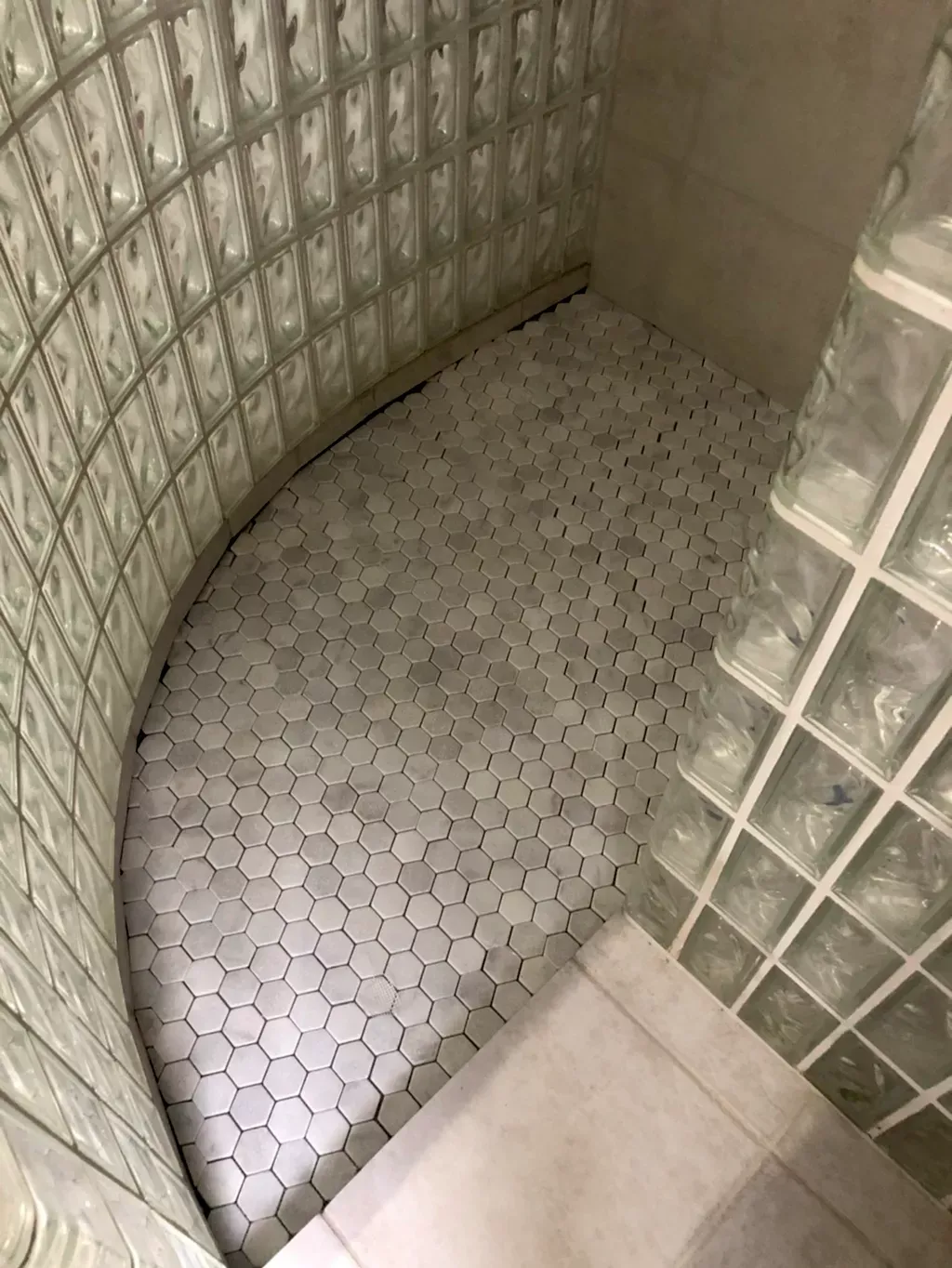 A bathroom with a curved shower surrounded by glass blocks.