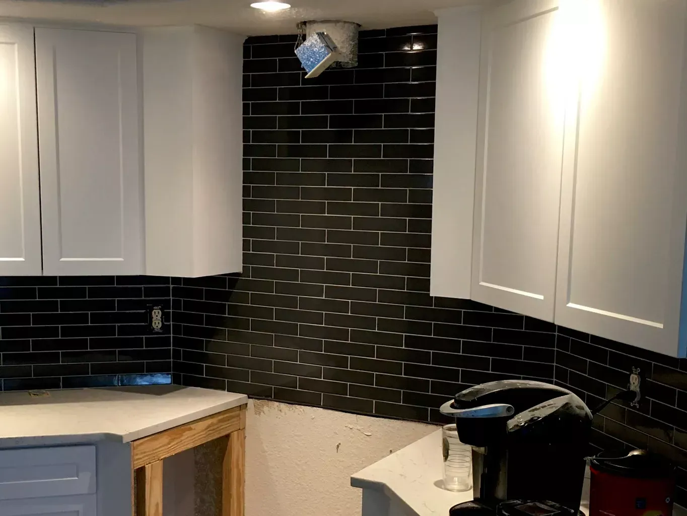 A kitchen with black tiles and white cabinets