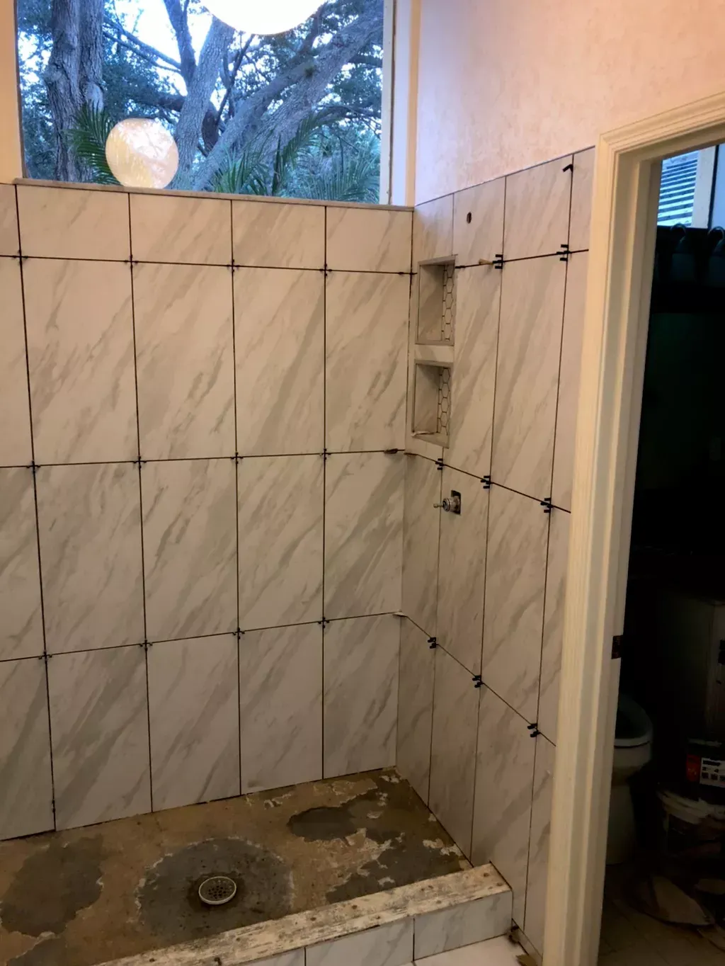 A bathroom with white tiles and a window.