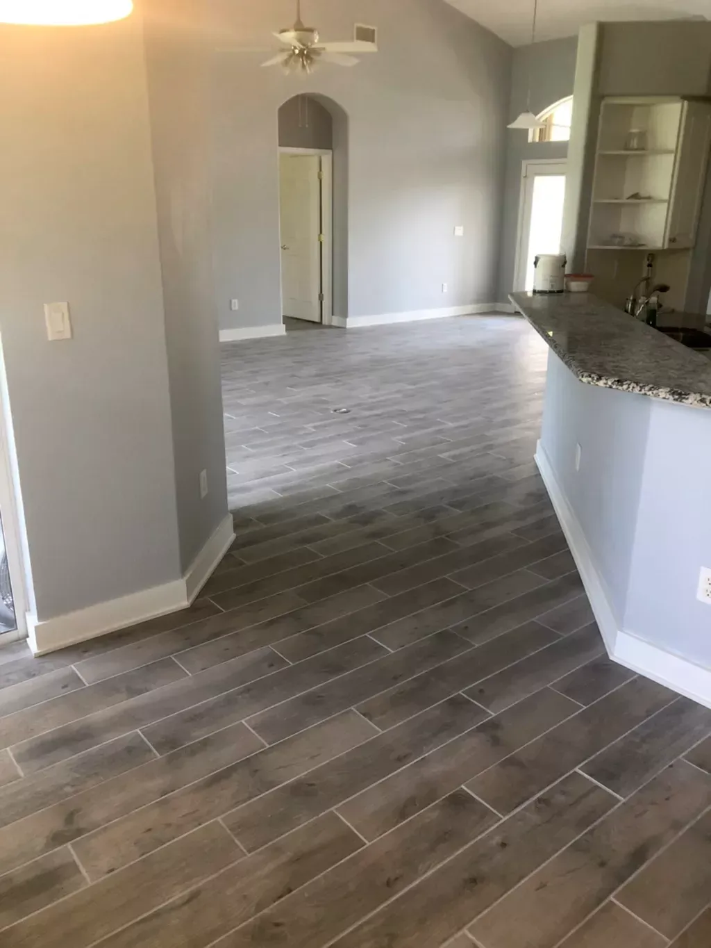 A living room with a wooden floor and a ceiling fan.