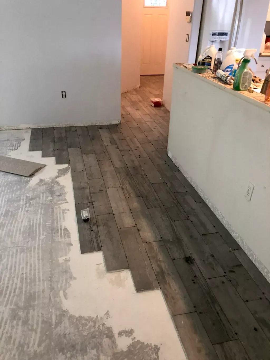 A wooden floor is being installed in a living room.