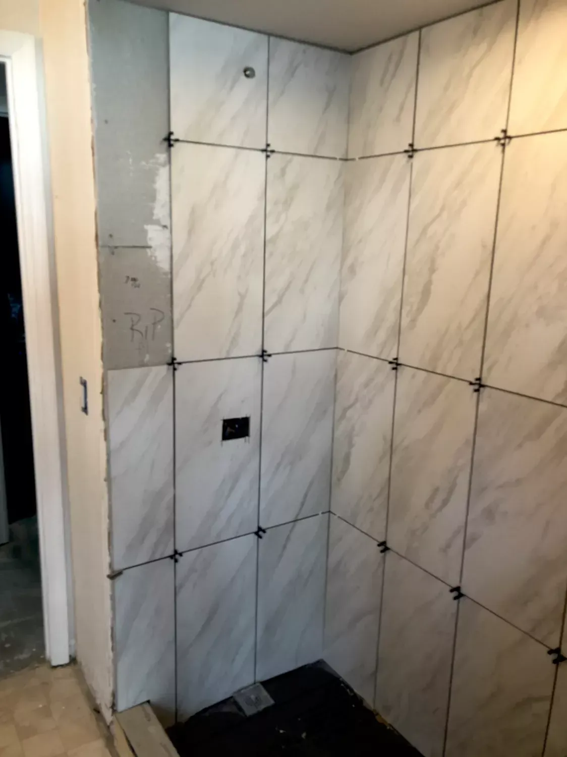 A bathroom with white tiles being installed on the wall