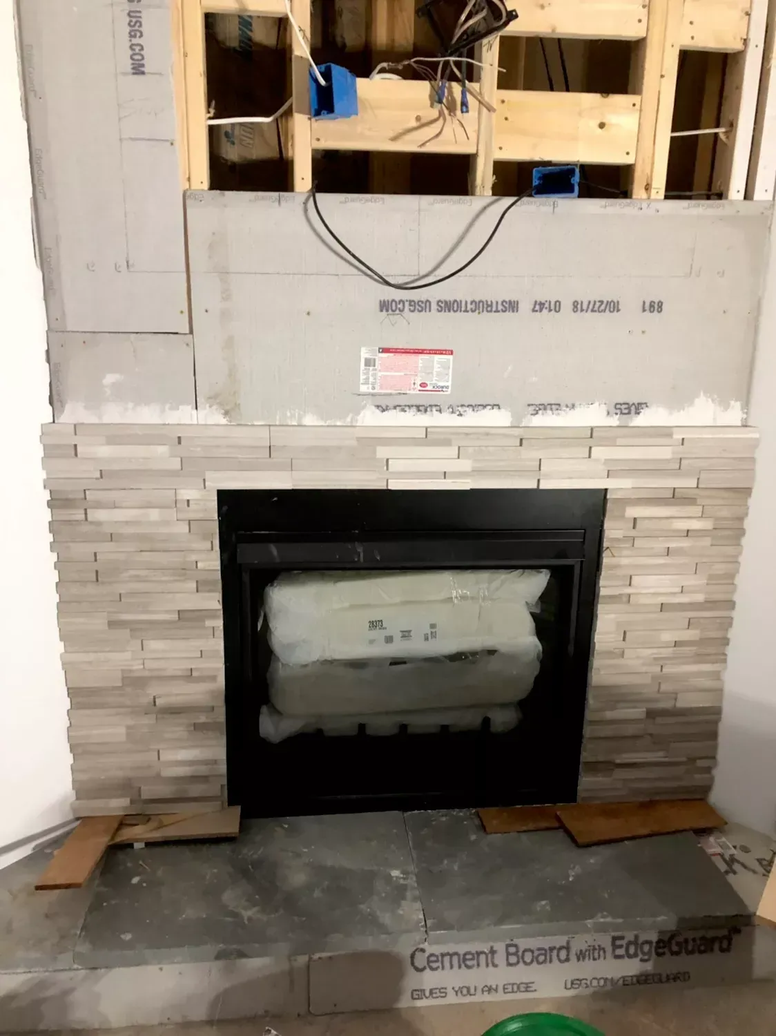 A fireplace is being built with cement board on the floor