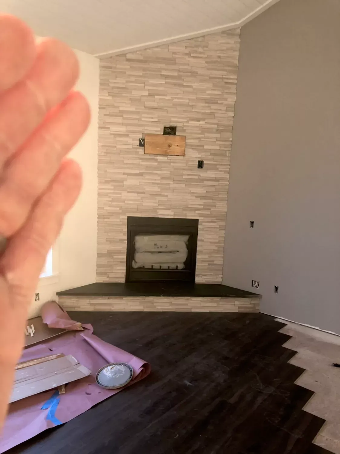 A person is holding a piece of paper in front of a fireplace in a living room.