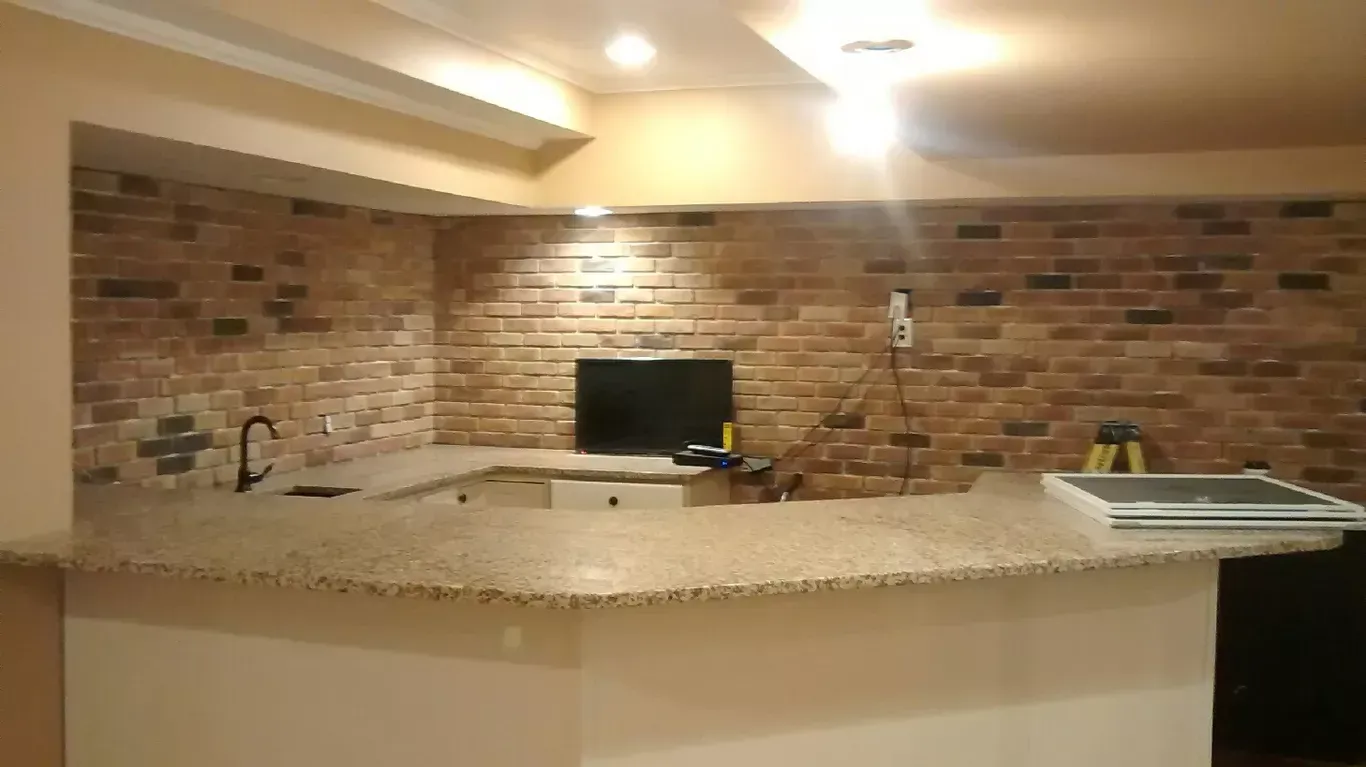 A kitchen with a brick wall and a granite counter top.