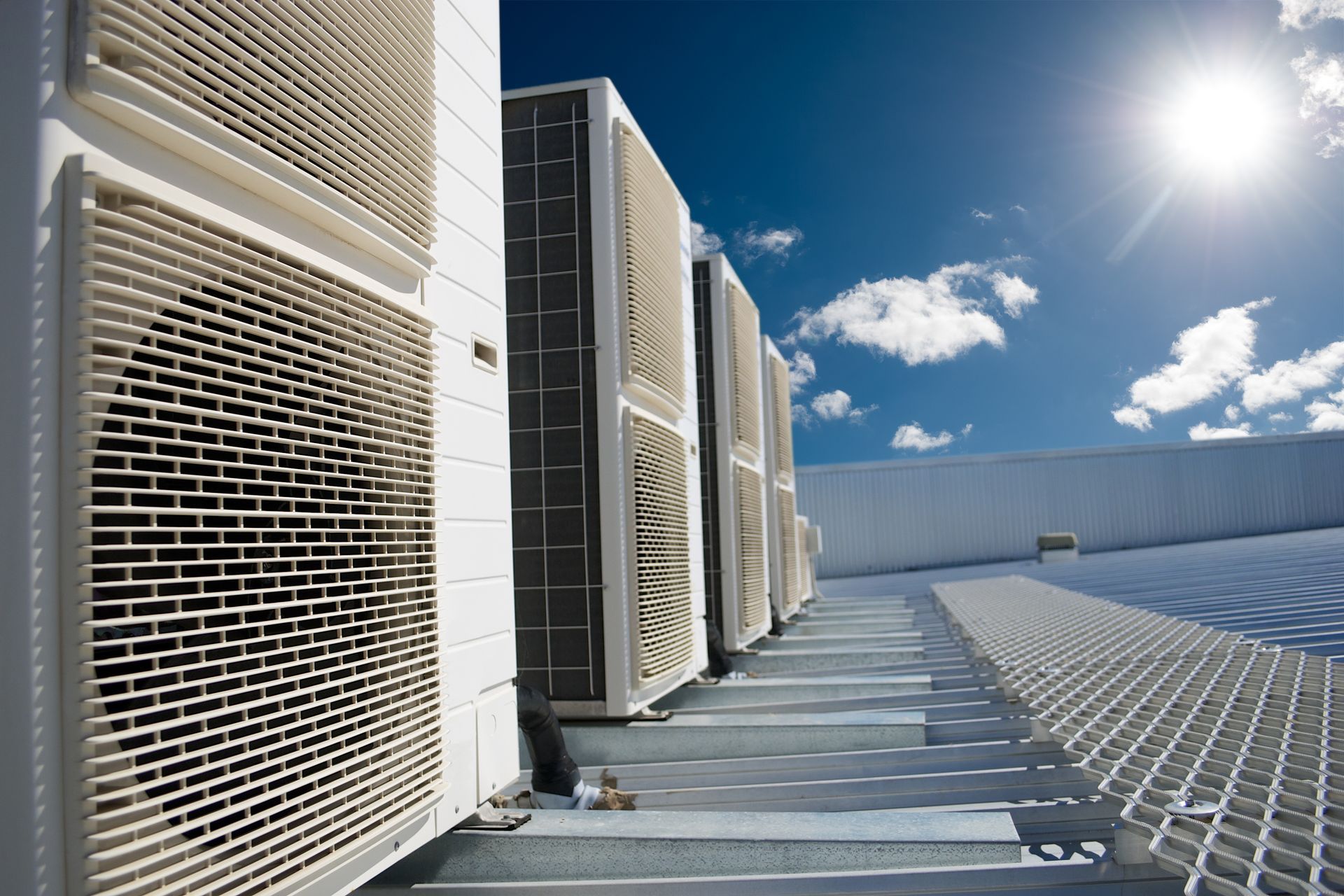 A row of air conditioners are lined up on the side of a building.