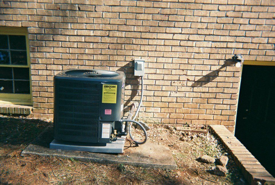 An air conditioner is sitting outside of a brick building