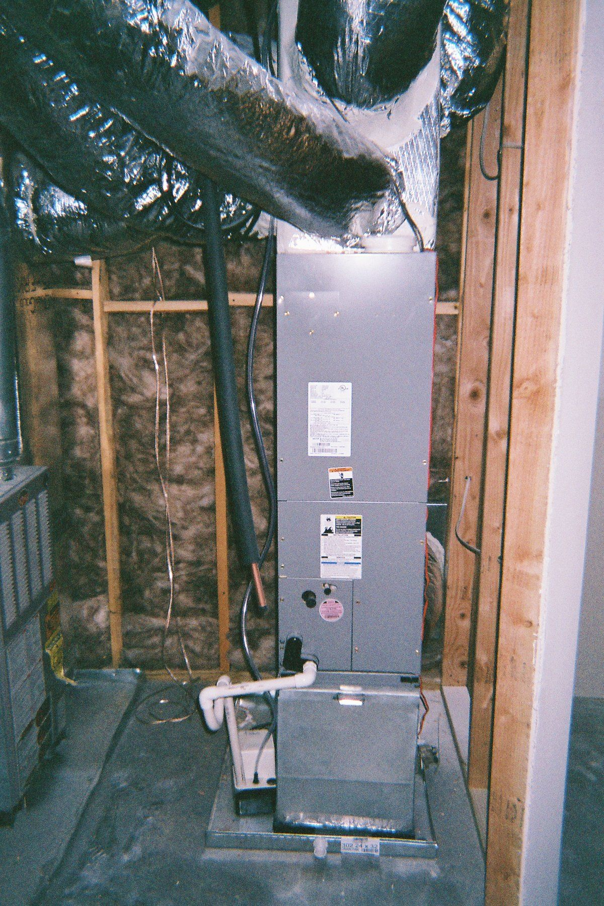 An air conditioner is sitting in a room with ducts coming out of it