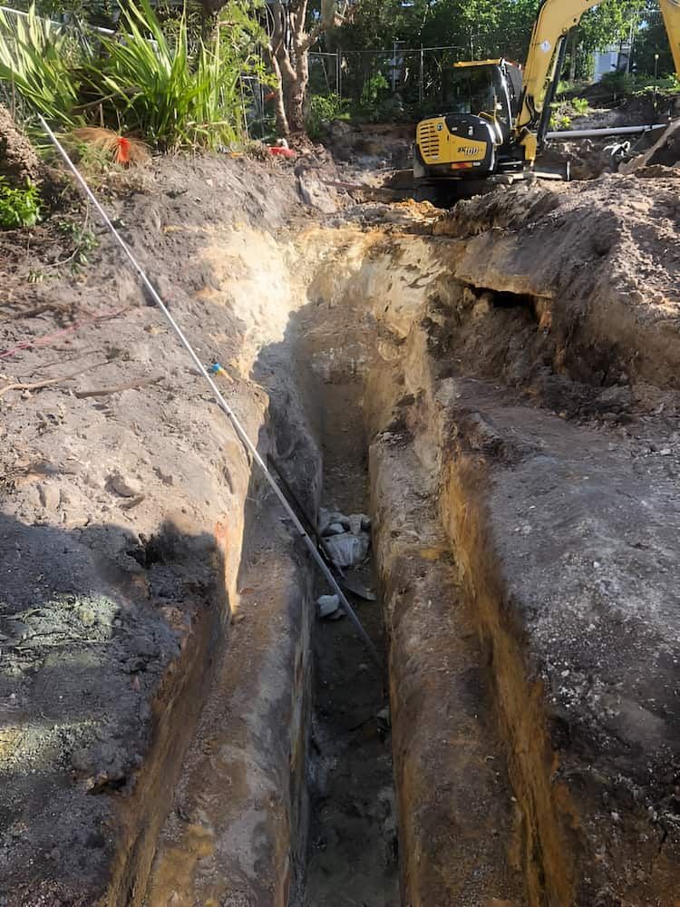 A Yellow Excavator is Digging a Trench in the Dirt — BeCivil in Berry, NSW