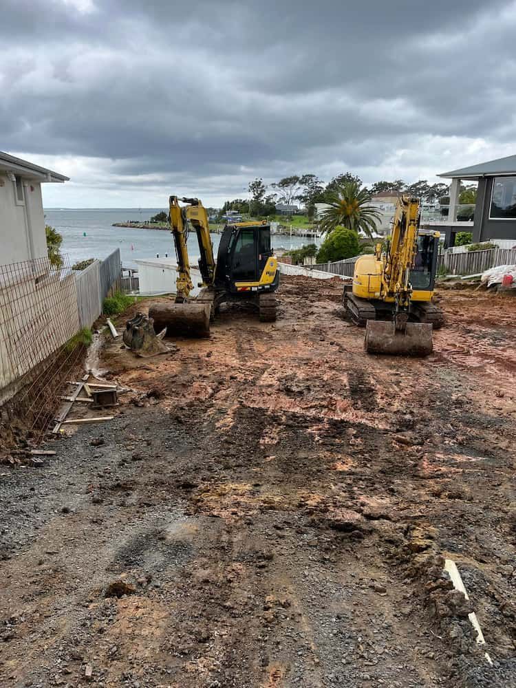 Two Yellow Excavators Are Working on a Dirt Road Next to a House — BeCivil in Vicentia, NSW