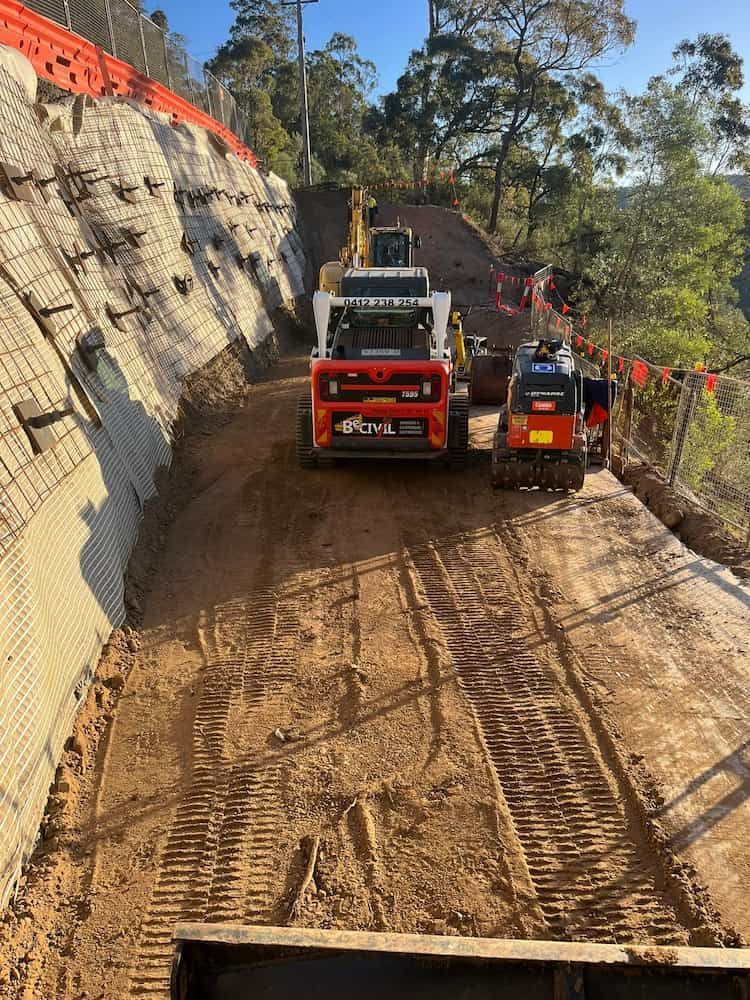 A Couple of Tractors Are Driving Down a Dirt Road — BeCivil in Berry, NSW