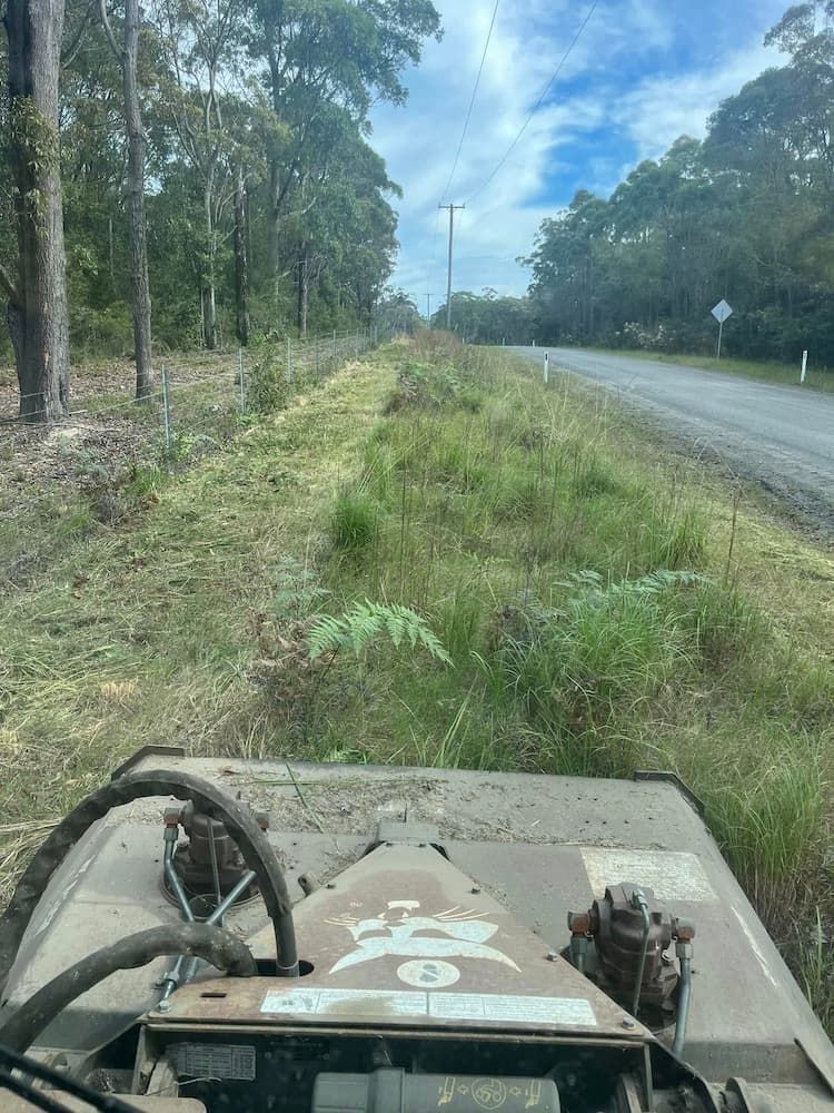 A Tractor is Cutting Grass Next to a Road — BeCivil in Tomerong, NSW