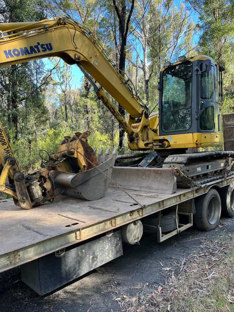 A Yellow Excavator is Sitting on Top of a Flatbed Truck — BeCivil in Tomerong, NSW