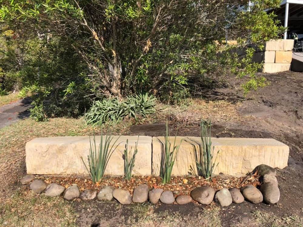 A Stone Bench With Plants and Rocks in a Garden — BeCivil in Ulladulla, NSW